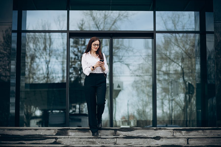 Business woman walking down the stairs and using phone